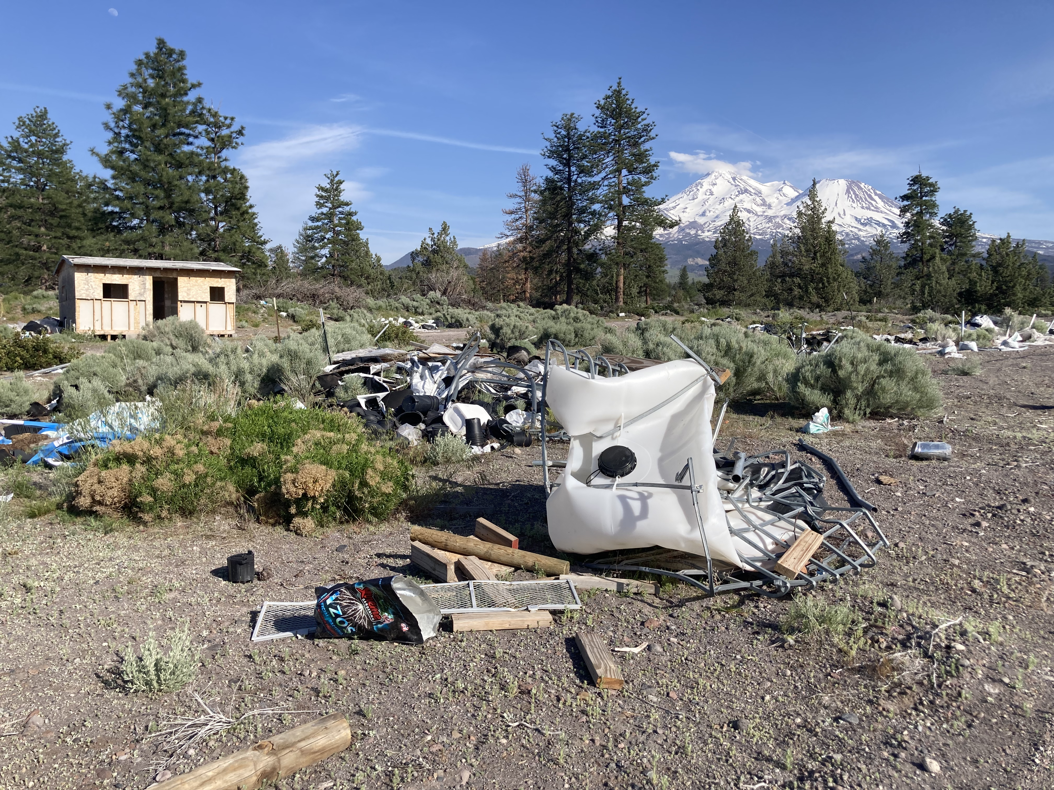 The site that was raided in 2021. Now, three years later, debris left unremediated poses considerable environmental harm risks. A typical plywood house is visible in the background.