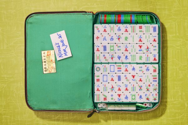 An open mahjong set shows tiles and game chips inside.