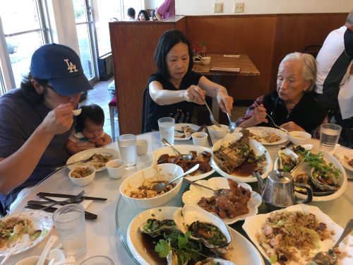 A family sits at a table in a restaurant with plates of food.